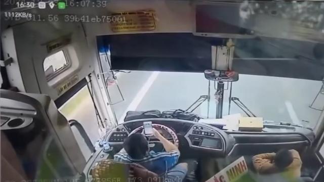 Tài xế xe giường nằm lái xe bằng khuỷu tay, mắt nhìn điện thoại